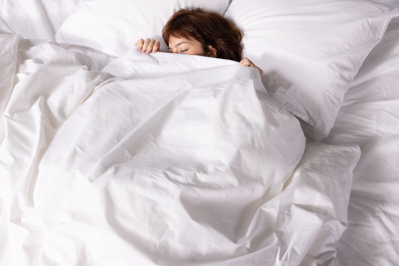 Vrouw die in bed ligt, met witte lakens